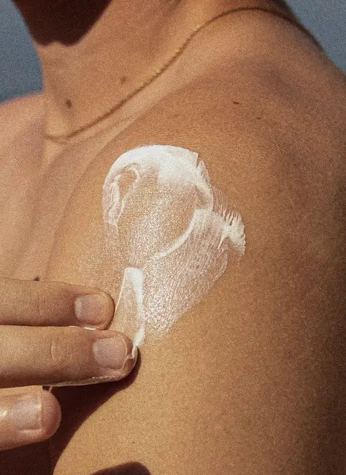 Hand applying lotion to their shoulder