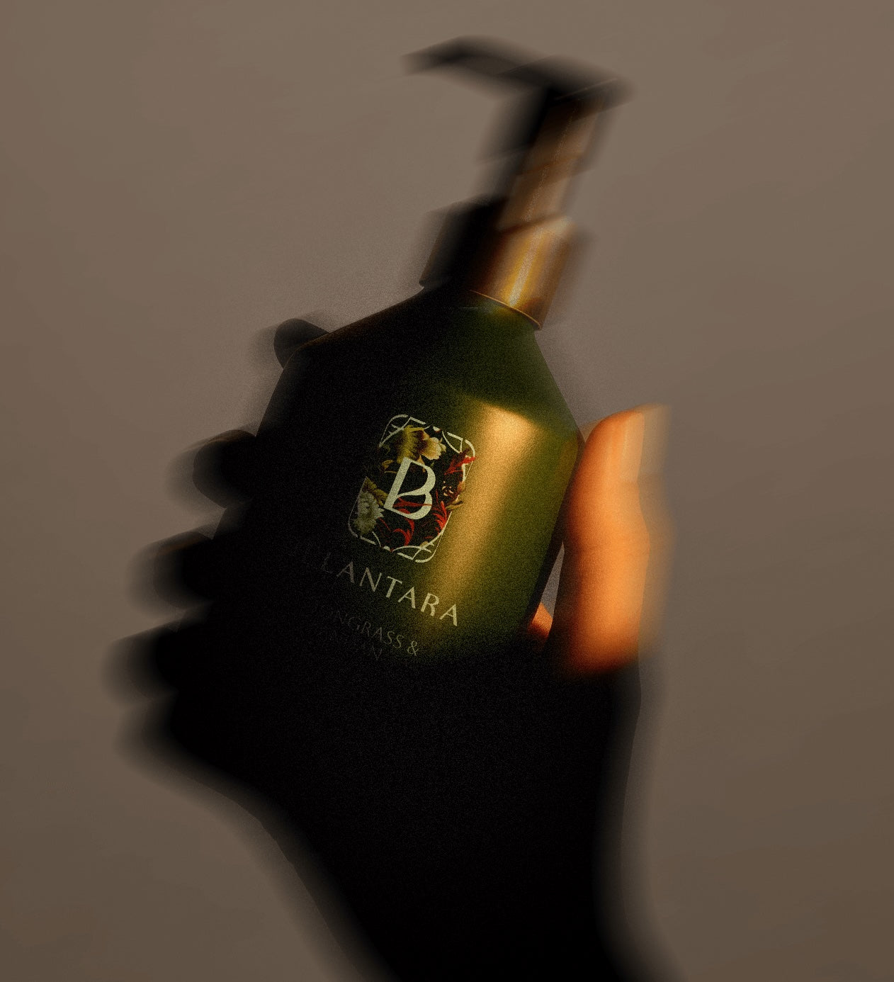 Hand holding a Belantara Hand & Body Wash bottle with a logo against a gray background.