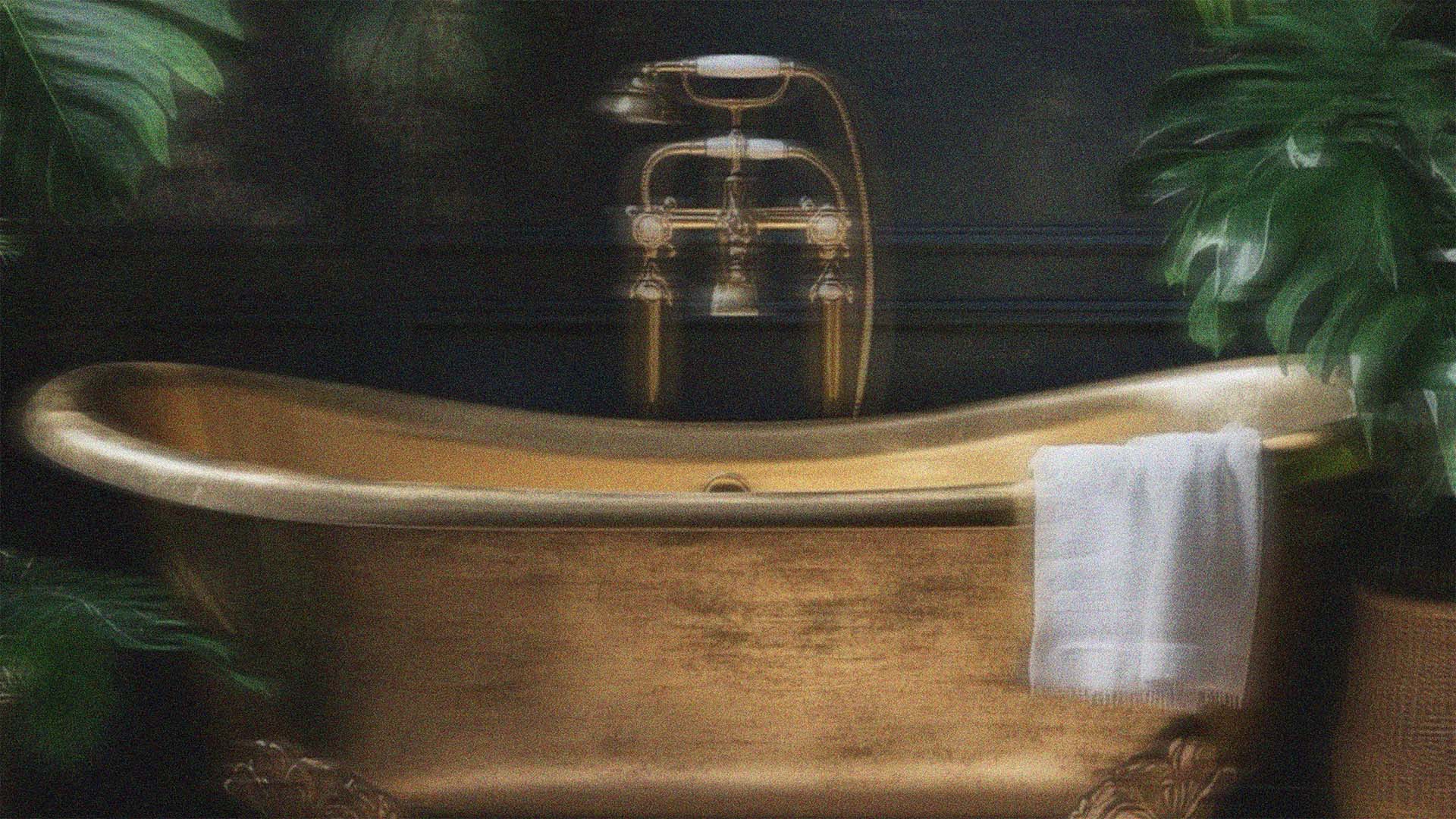 An opulent brass Victorian bathtub surrounded by tropical leaves in the Southeast Asian tropical rainforest.