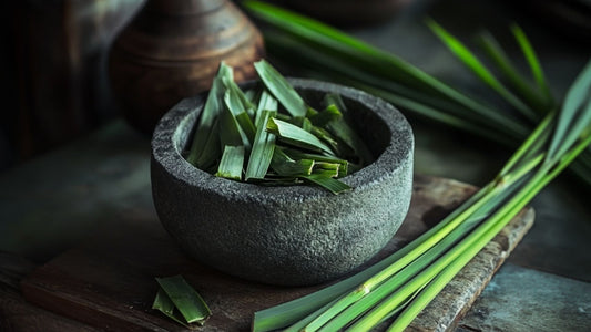 A traditional stone bowl filled with cut pandan leafs in a traditional Southeast Asian kitchen setting.