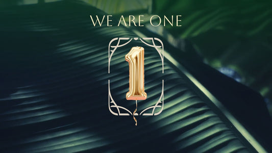 A golden ballon with the shape of the number 1 over a background of a tropical leave.