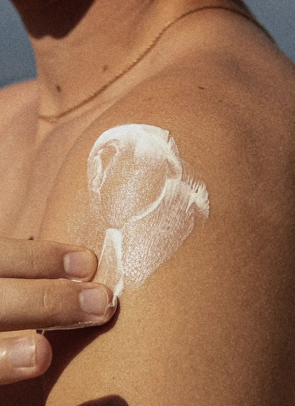 Hand applying lotion to their shoulder