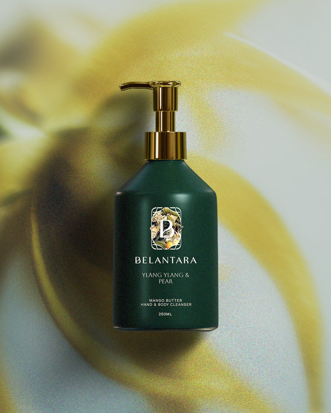 Green bottle with gold pump of Belantara Mango Butter Hand & Body Cleanser in Ylang Ylang & Pear fragrance on a textured ylang ylang background.