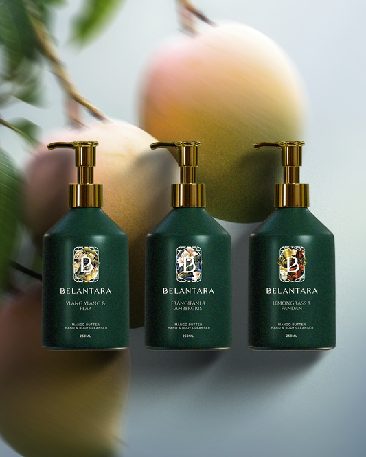 Three green bottle with gold pump of Belantara Mango Butter Hand & Body Cleanser on a textured mangoes background.