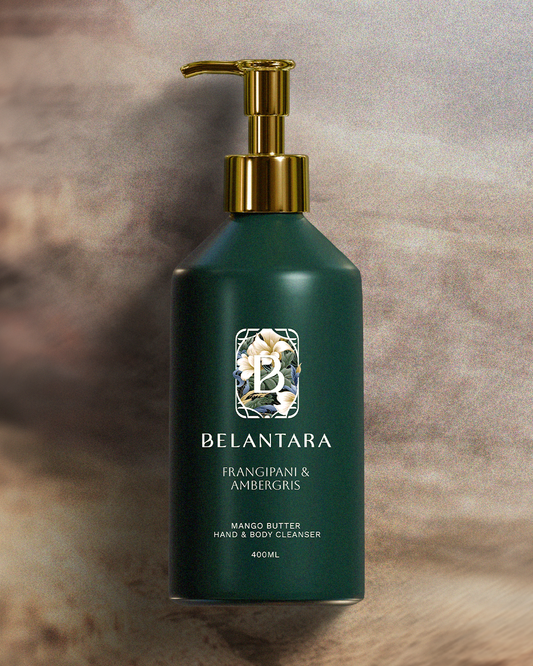 Green bottle with gold pump of Belantara Mango Butter Hand & Body Cleanser in Frangipani & Ambergris fragrance on a textured brown background.