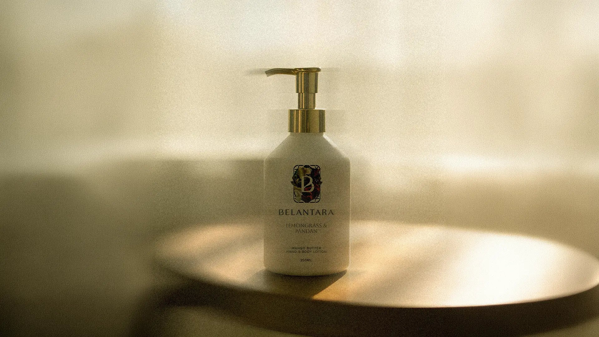 Bottle of Belantara mango butter hand and body lotion on a wooden surface, softly lit.