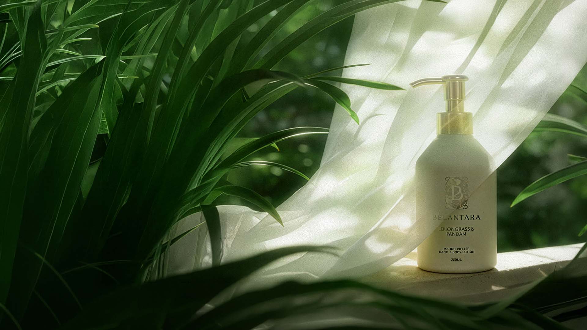 A bottle of Belantara Mango Butter Hand & Body Lotion on a white surface with tropical leaves in the background.